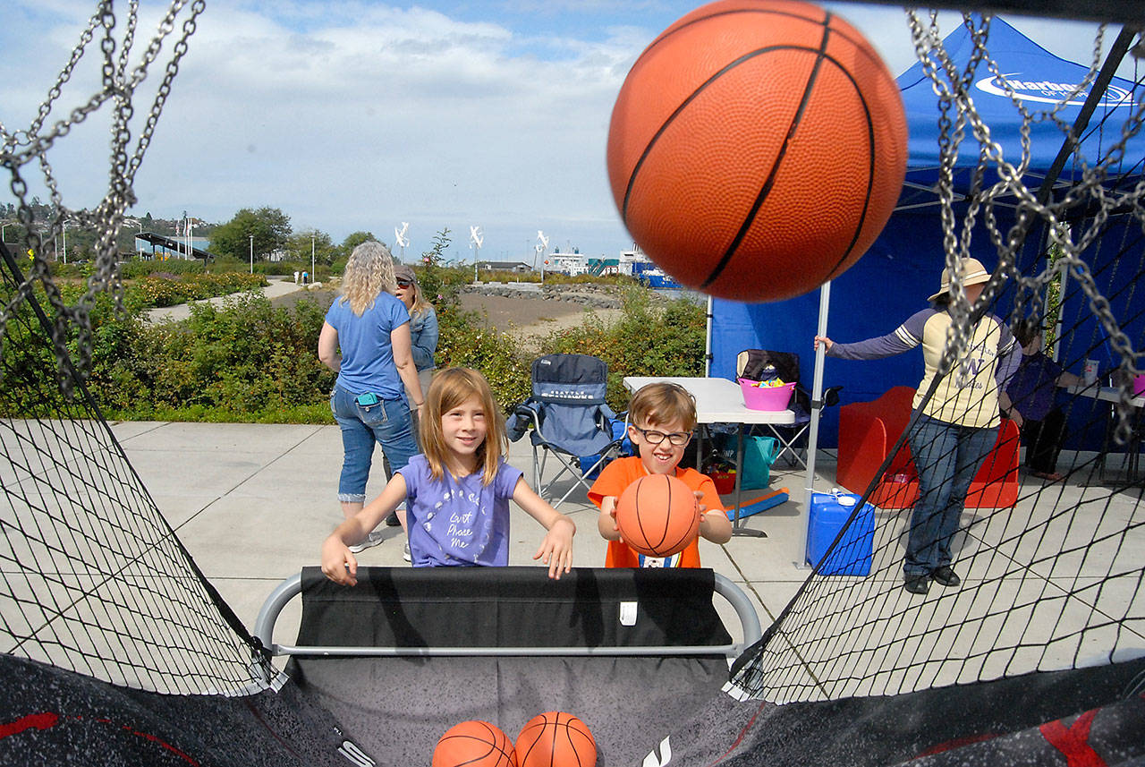 From left, cousins Ivy Bishop, 7, of Bellingham and Maeve Caron, 6, of Portland, Ore., toss basketballs during a hoops game set up at Pebble Beach Park in Port Angeles during Saturday’s Jammin’ in the Park. (Keith Thorpe/Peninsula Daily News)