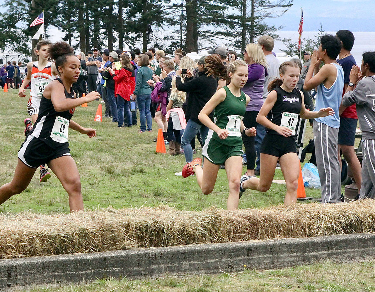 Port Angeles’ Lauren Larson (1) of and Sequim’s Riley Pyeatt (47) are stride-for-stride as they jump the first hurdle at the start of the race in girls varsity race at the Salt Creek Invitational Cross-Country meet Saturday. Larson won the race for the second straight year, beating her winning time from last year by a full minute. (Dave Logan/for Peninsula Daily News)