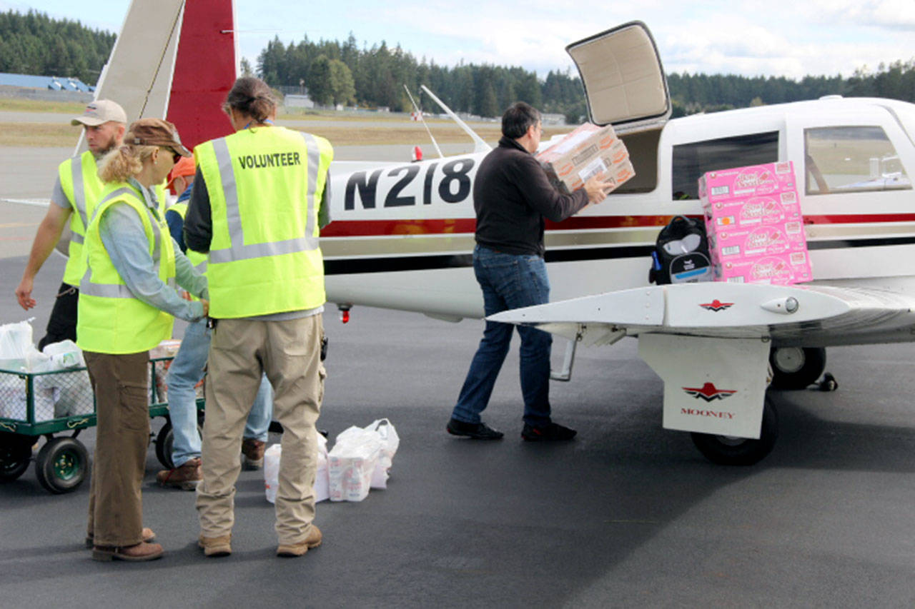 Ground support volunteers Mike and Shari Sanford and Shane Trullinger help pilot Matt Frehner load donated food into his plane during a Clallam County Disaster Airlift Response Team exercise Sept. 21.