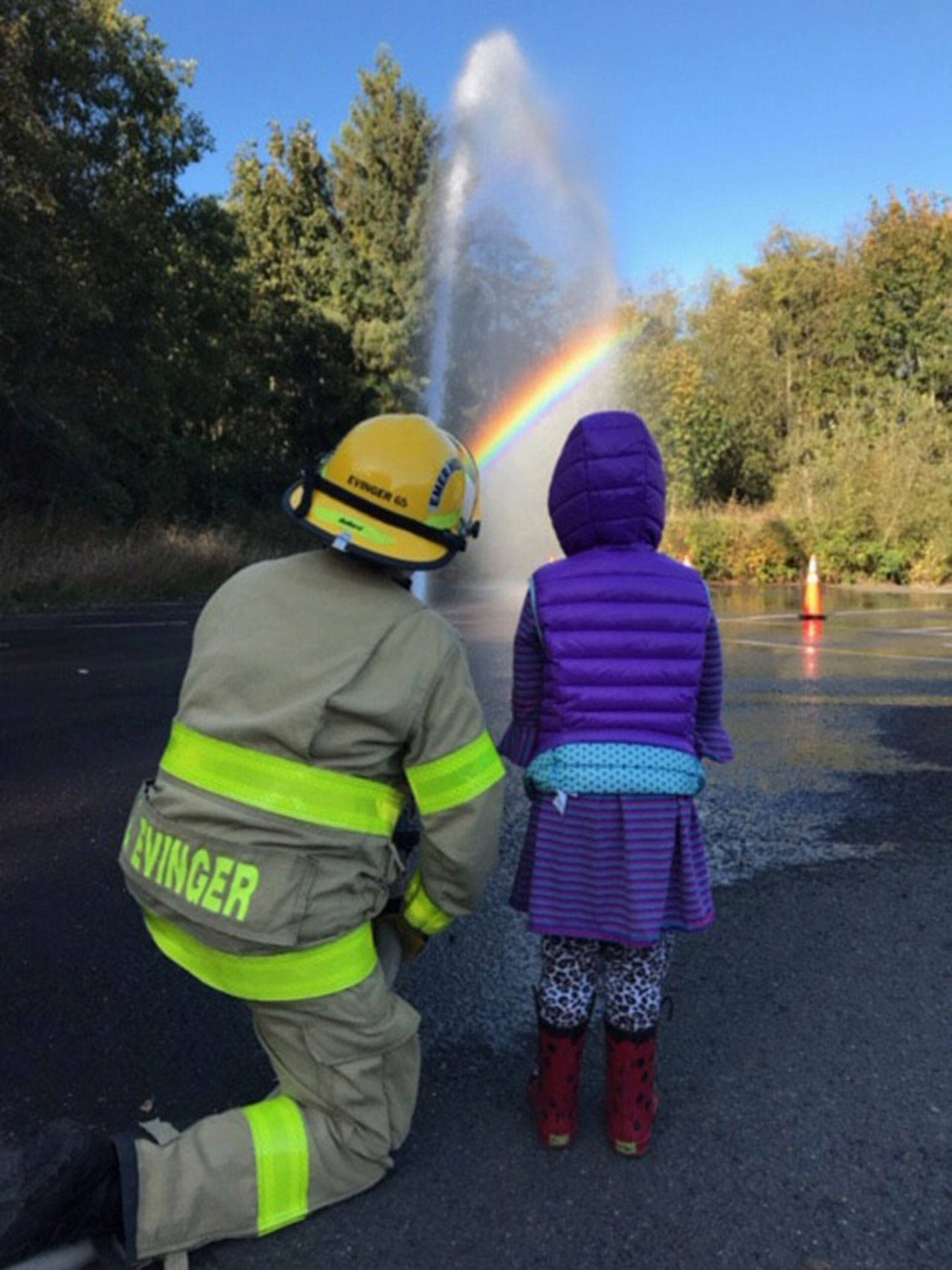Clallam County Fire District No. 4 EMT Lee Evinger and Crescent School kingergarten student Aryanna Tenneson “man the hose” during a recent school fire safety training day. (Clallam Fire District No. 4)