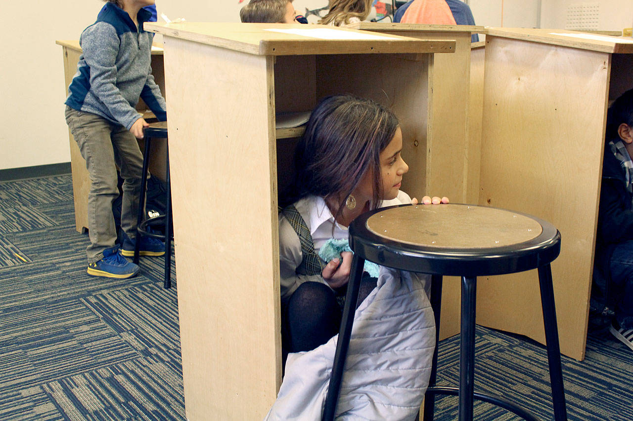 Chimacum third grade student Kylie Palladeno starts to climb out from under her desk during the Great ShakeOut earthquake drill Thursday. (Zach Jablonski/Peninsula Daily News)