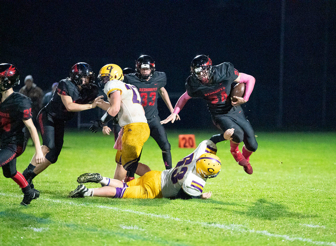 Steve Mullensky/for Peninsula Daily News Redhawk Dylan Tracer takes to the air to get around Concrete Lion Shawn Powell during a game on Friday at Memorial Field in Port Townsend.