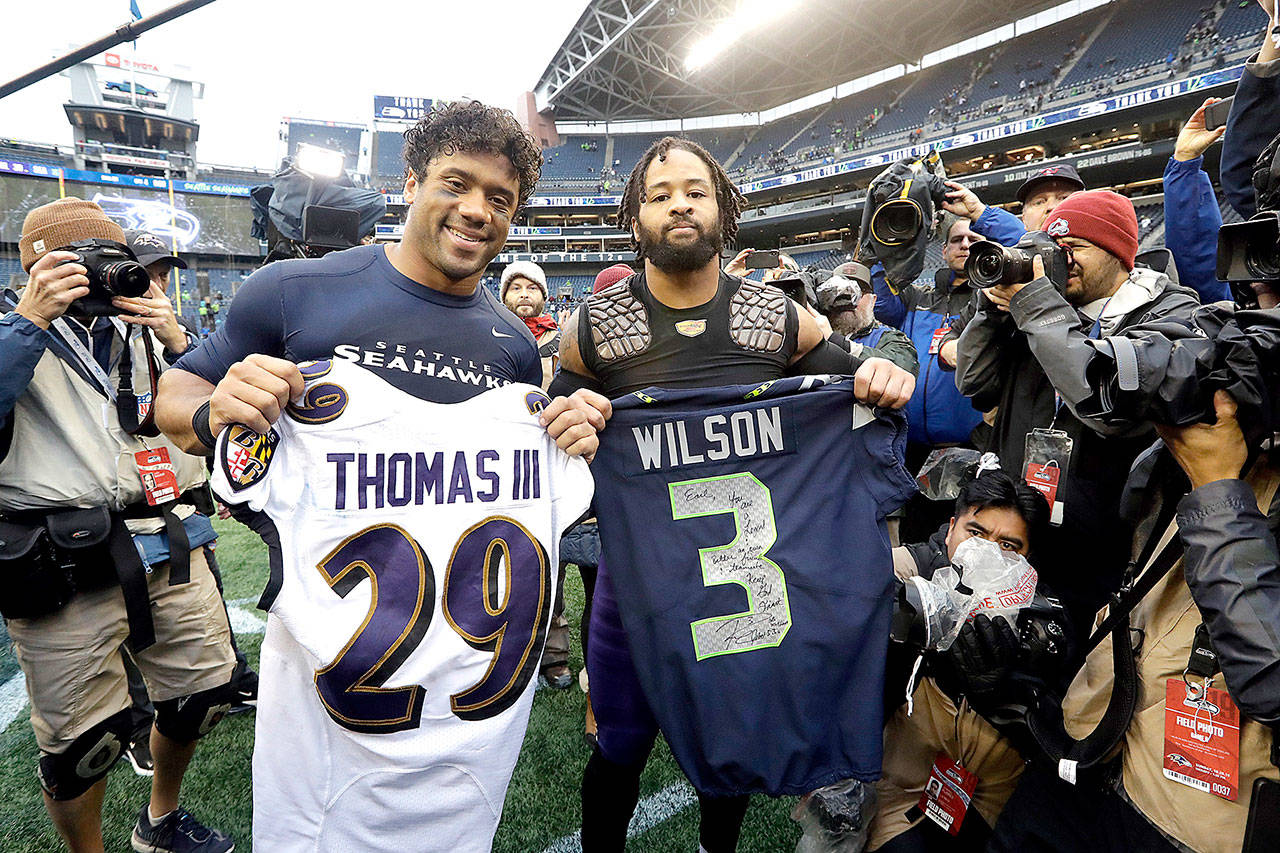 Seattle Seahawks quarterback Russell Wilson, left, and Baltimore Ravens free safety Earl Thomas, right, pose for a photo after they traded jerseys following an NFL football game, Sunday, Oct. 20, 2019, in Seattle. (AP Photo/Elaine Thompson)