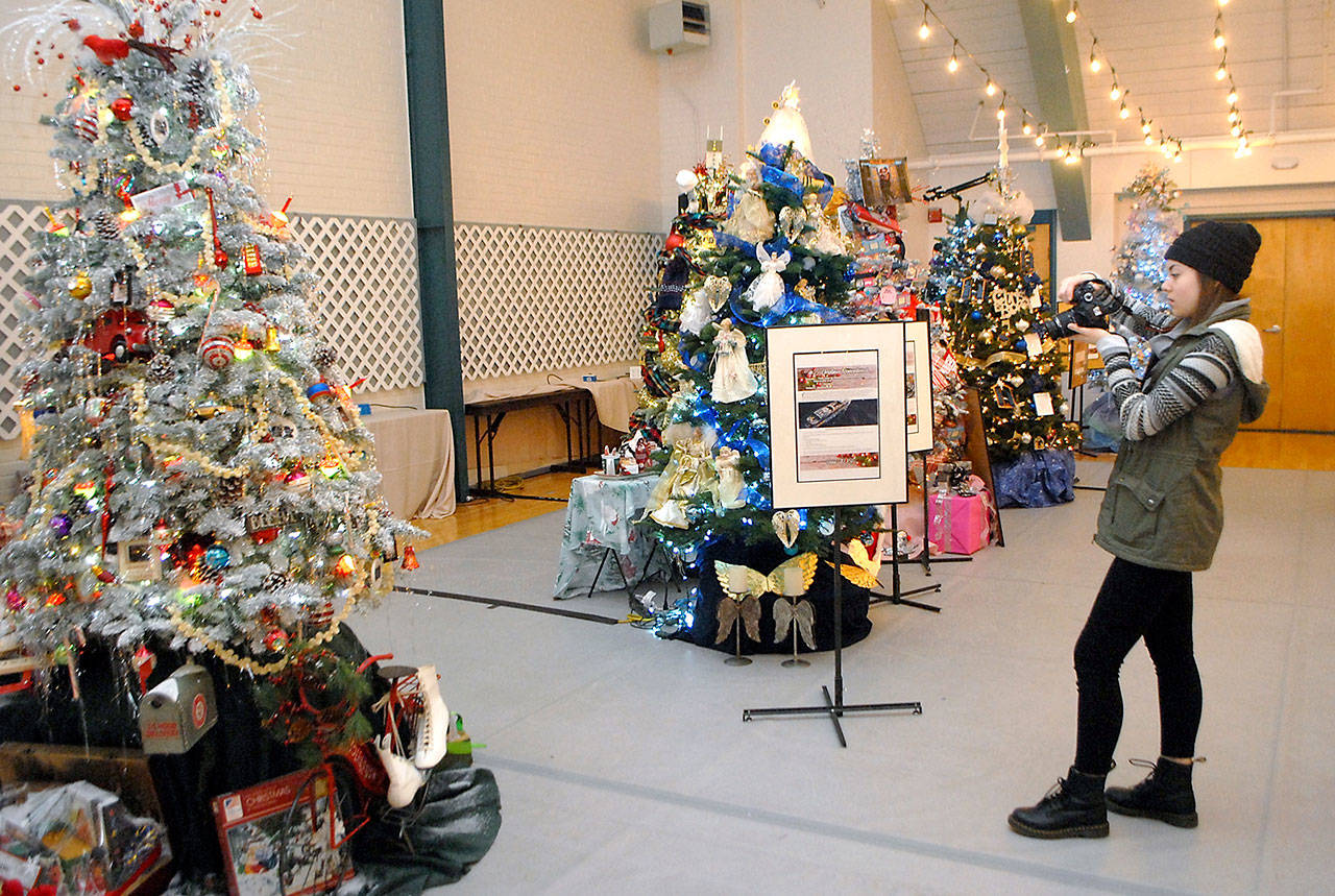 Liliana Williams, an intern with the Olympic Medical Center Foundation, takes photographs of finished Christmas trees Wednesday in preparation for this weekend’s Festival of Trees at Vern Burton Community Center. (Keith Thorpe/Peninsula Daily News)