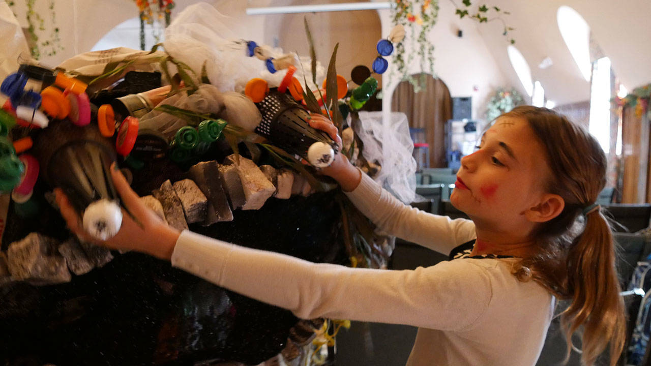 Young thespian Marea Denton helps with costuming on the “Garbage Monster,” a recurring character in the Tidepool Times saga. (Olympic Theatre Arts)