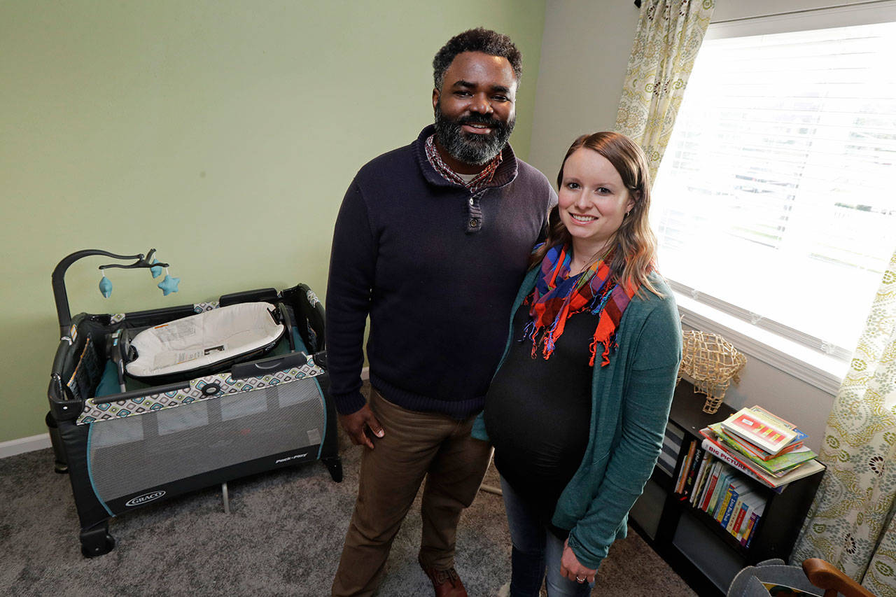 Kate and Quantas Ginn pose for a photo Sunday in their home in Tacoma in the bedroom they are preparing ahead of the upcoming birth of their baby in late January. Kate Ginn is planning to submit paperwork Thursday to apply for paid time off from her job as a project manager for a nonprofit organization under Washington’s new paid family leave law. (Ted S. Warren/The Associated Press)