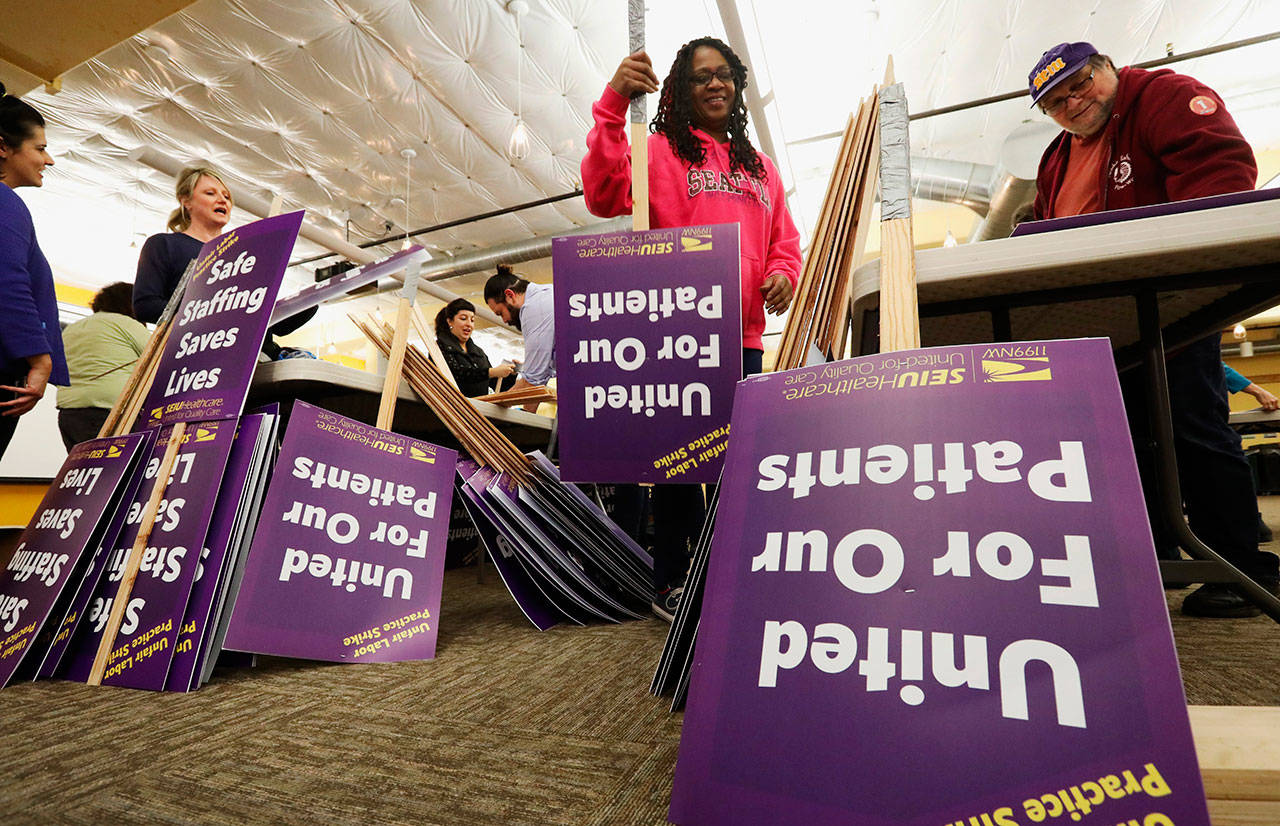 Valarie Howard, second from right, a certified nursing assistant at Swedish First Hill, makes picket signs in Seattle on Monday, Jan. 27, 2020, as they plan to strike Tuesday. Nurses and caregivers from Swedish hospital have notified the hospital that they will strike for three days at all of the medical center’s locations in the Seattle region. (Ken Lambert/The Seattle Times via AP)