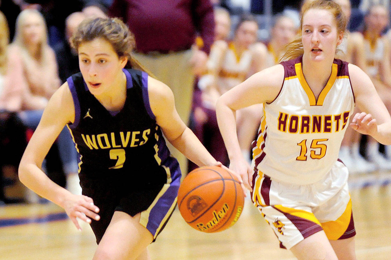 Sequim Wolves guard Jessica Dietzman (2) drives up the court with White River Hornets guard Kara Marecle (15) in close pursuit. Dietzman lead the Wolves in scoring with 14 points while Marecle had a game-high 22 as the Hornets beat the Wolves 57-53 in a district playoff loser-out game on Feb. 20 to qualify for the regional round of the 2A State Championships. (Conor Dowley/Olympic Peninsula News Group)