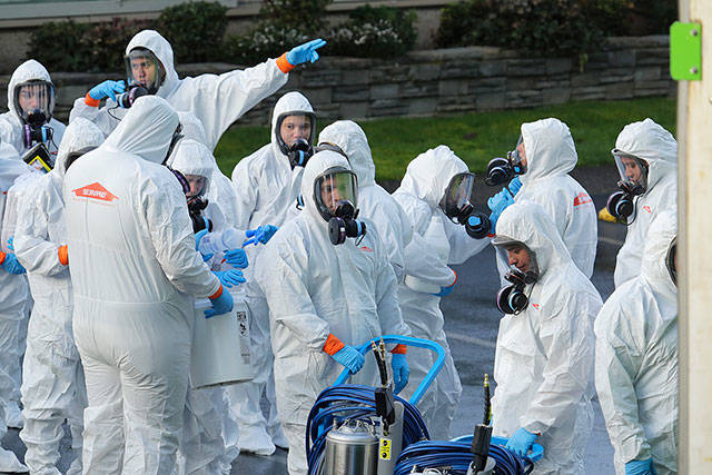 Workers from a Servpro disaster recovery team wearing protective suits and respirators enter the Life Care Center in Kirkland, Wash., to begin cleaning and disinfecting the facility, Wednesday, near Seattle. The nursing home is at the center of the coronavirus outbreak in Washington state. For most people, the virus causes only mild or moderate symptoms. For some it can cause more severe illness, especially in older adults and people with existing health problems. (Ted S. Warren/The Associated Press)