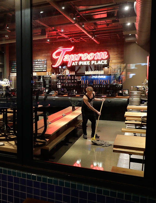 Tyler Baldwin mops the floor after closing for the night at the Taproom at Pike Place on Sunday, March 15, 2020, where he works as a bartender in Seattle. Washington Gov. Jay Inslee said Sunday night that he would order all bars, restaurants, entertainment and recreation facilities in the state to temporarily close to fight the spread of the COVID-19 coronavirus, as Washington state has by far the most deaths in the U.S. from the disease. Baldwin said he closed more than an hour early Sunday after he heard the announcement. (Ted S. Warren/The Associated Press)