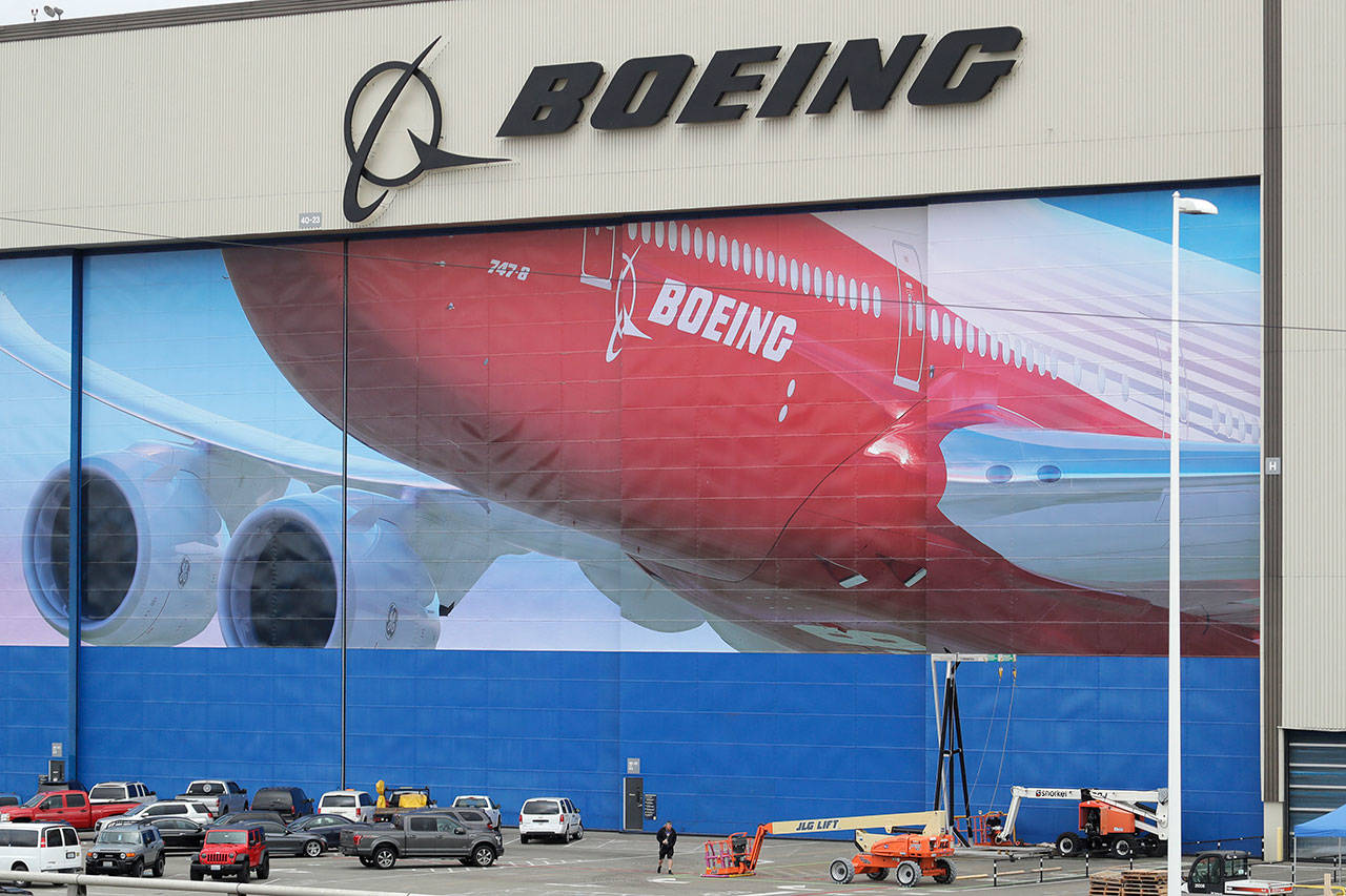A worker walks near a mural of a Boeing 747-8 airplane at the company’s manufacturing facility in Everett on Monday, March 23, 2020, north of Seattle. Boeing announced Monday that it will be suspending operations and production at its Seattle area facilities due to the spread of the new coronavirus. (Ted S. Warren/The Associated Press)