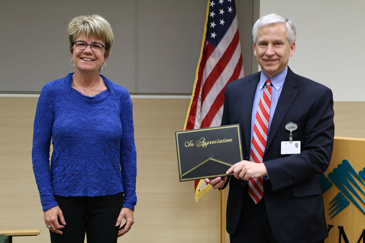 Eric Lewis, retiring chief executive officer at Olympic Medical Center, receives an engraved compass with appreciation for his leadership and support of community wellness from Dr. Monica Dixon, co-founder of The Olympic Peninsula Healthy Community Coalition. (Submitted photo)