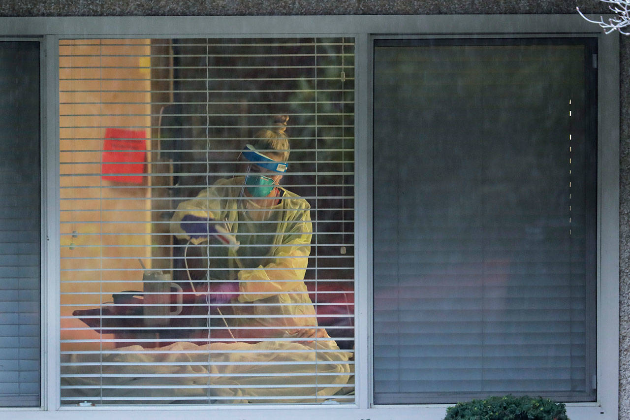 In this March 13, 2020, file photo, a nurse works in the room of a patient who has tested positive for the COVID-19 coronavirus at the Life Care Center in Kirkland near Seattle. Nursing home outbreaks of COVID-19 have raised concern in the U.S. since widespread infection at the Kirkland facility led to dozens of deaths. (Ted S. Warren/Associated Press file)