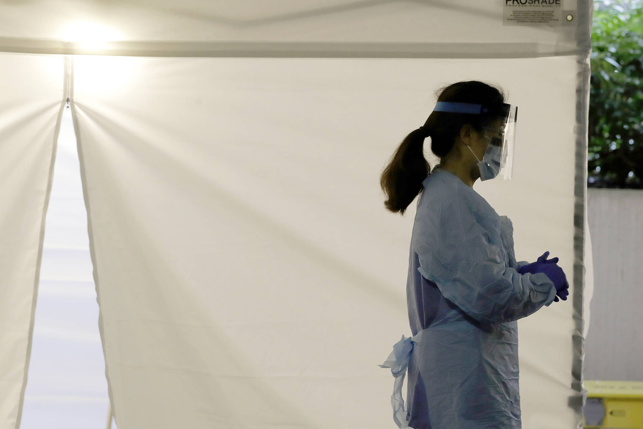 A nurse at a drive-up coronavirus testing station set up by the University of Washington Medical Center wears a face shield and other protective gear in this March 13 file photo as she waits by a tent in Seattle. Experts and health officials who are trying to plan a response to the coronavirus outbreak are missing a critical piece of information – the number of health care workers who have tested positive for the disease. (Ted S. Warren/The Associated Press)