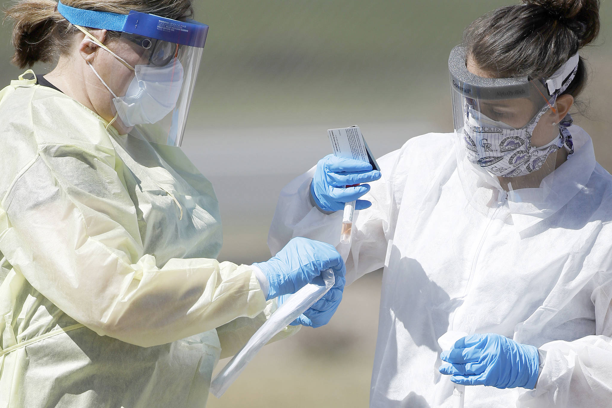 Medical technicians handle a vial containing a nasal swab at a drive-thru testing site in Wheat Ridge, Colo., in this March 31 file photo. Home testing for coronavirus may sound like a good idea, but as of this week, U.S. regulators say it’s still too risky. (David Zalubowski/The Associated Press)