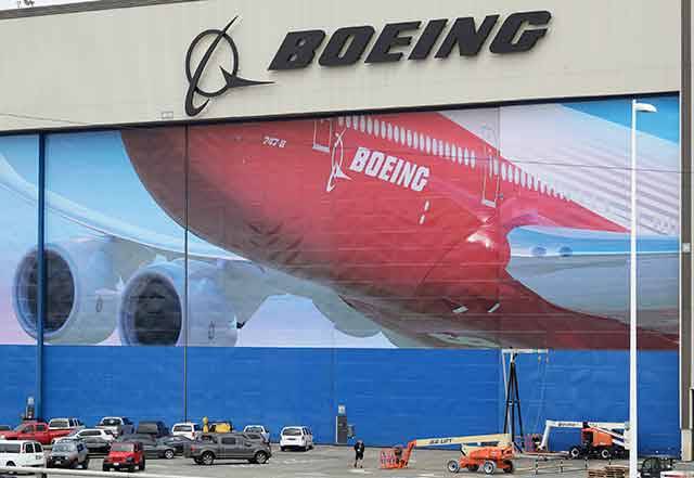 A worker walks near a mural of a Boeing 747-8 airplane at the company’s manufacturing facility in Everett in this March 23 file photo. In an email to Washington employees on Sunday, the company said it is extending a planned two-week shutdown rather than reopening Wednesday due to coronavirus concerns. The decision affects about 30,000 of Boeing’s 70,000 employees in the state. Employees are receiving their regular salaries during the two-week shutdown but will have to transition to vacation or sick leave after that. (Ted S. Warren/The Associated Press)