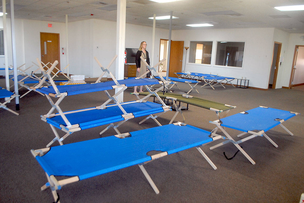 Jess Pankey, an environmental health specialist with Clallam County Heath and Human Services, looks over a room filled with cots Thursday, April 9, 2020, at the Port of Port Angeles’ 1010 Building near William R. Fairchild International Airport, as the building is converted to an isolation shelter for homeless individuals who might be infected with the novel coronavirus. (Keith Thorpe/Peninsula Daily News)