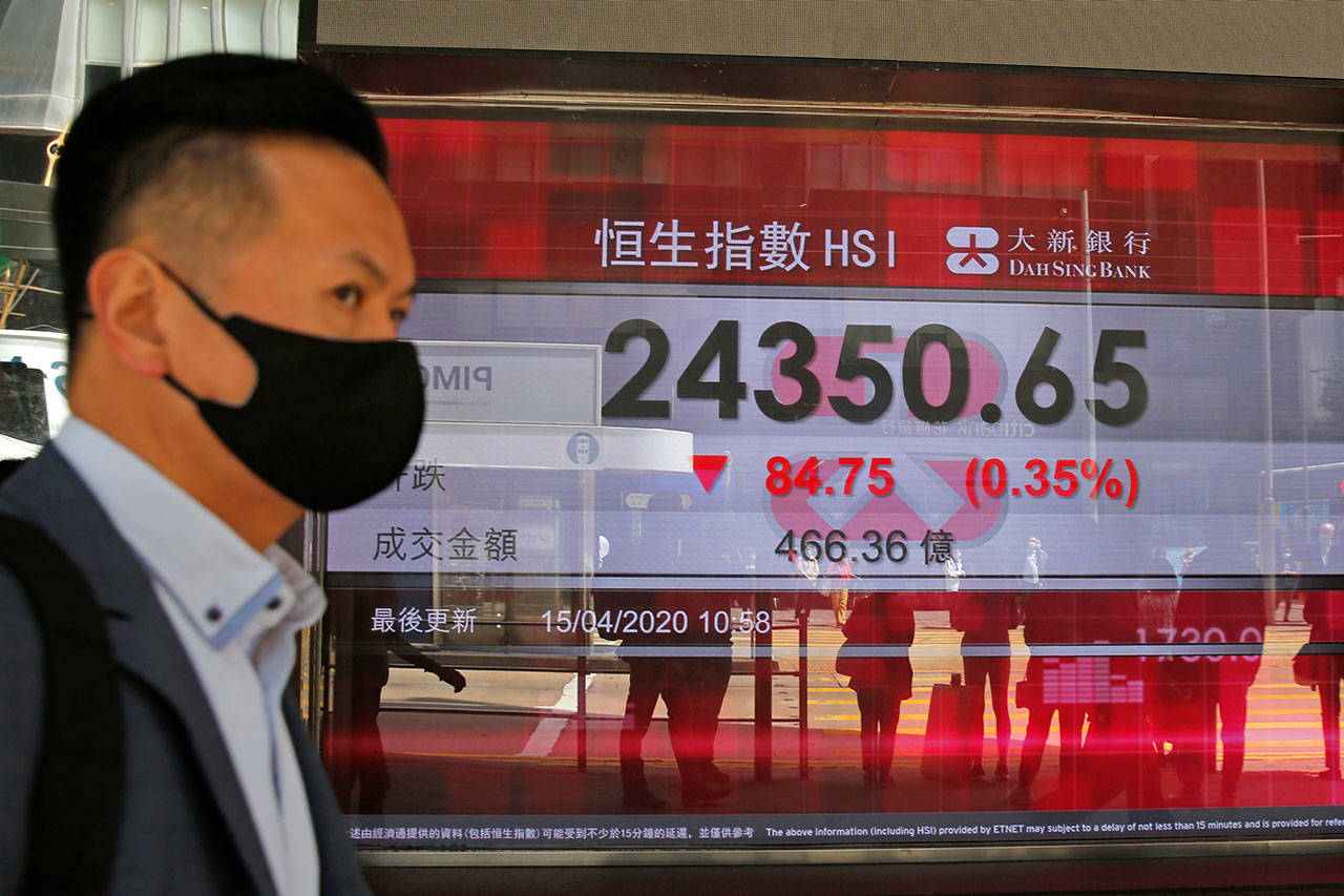 A masked man walks past an electronic board showing Hong Kong share index outside a local bank in Hong Kong on Wednesday, April 15, 2020. Asian stocks edged lower Wednesday after the International Monetary Fund said the global economy will suffer its worst year since the Great Depression of the 1930s due to the coronavirus pandemic. (AP Photo/Kin Cheung)