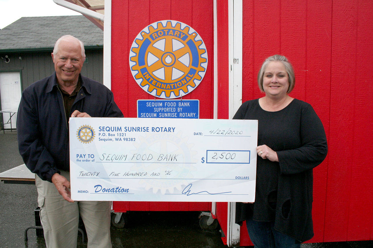 Andra Smith, executive director of Sequim Food Bank, accepts a $2,500 donation from Russ Mellon, president of Sequim Sunrise Rotary.