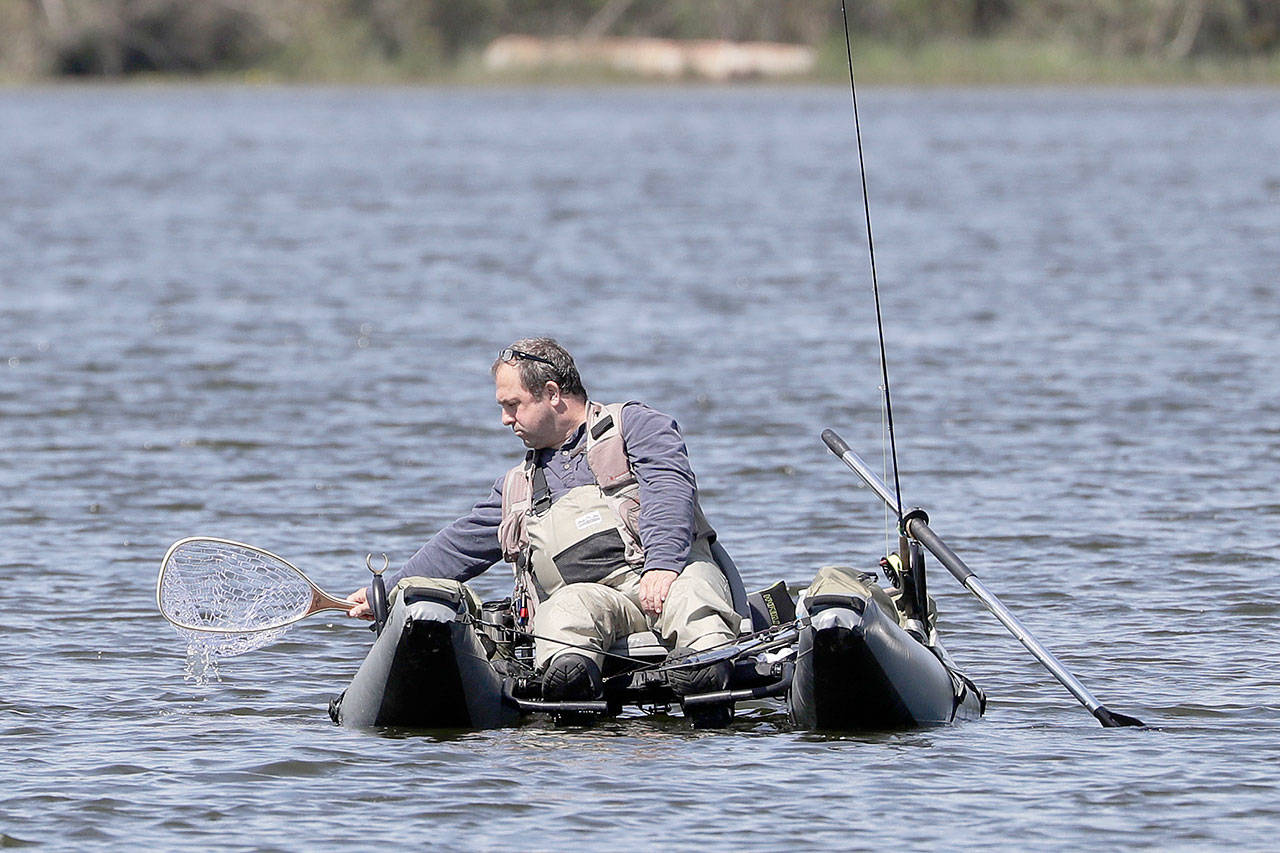 An angler dips his net into Blackmans Lake while fishing on the first day of a partial reopening of outdoor recreation activities Tuesday, May 5, 2020, in Snohomish. Washington state parks, public lands and public water-access points have been closed since late March in an effort to slow the spread of the novel coronavirus. Recreational fishing seasons were closed a few days later when Inslee first issued his “stay-home” order to slow the virus. (Elaine Thompson/Associated Press)