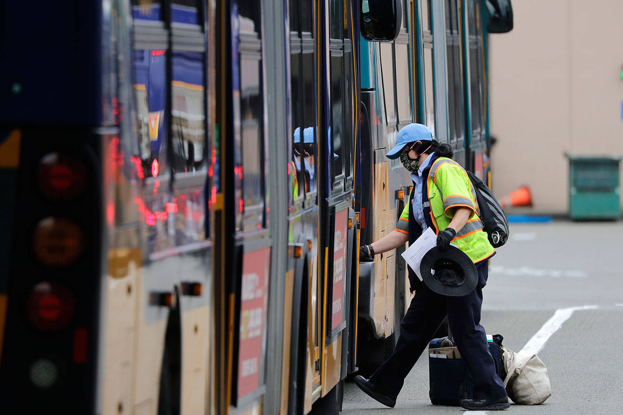 A King County Metro bus driver wipes down a handrail before stepping onto a bus Monday in Seattle. The coronavirus pandemic has plunged Puget Sound-area transit agencies into crisis-planning mode, as ridership and revenue has plunged and predictions that people will not be returning to buses and trains in large numbers any time soon. (AP Photo/Elaine Thompson)