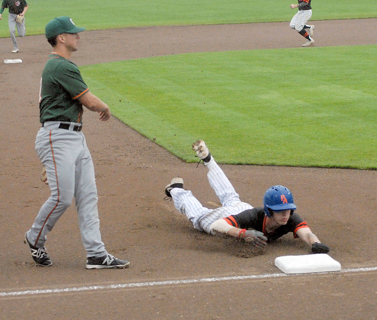 Lefties baserunner Gavin Rork dives into third on an errant pitch as Cowlitz third baseman Andres Sosa waits for a throw from home during a 2019 game at Civic Field. (Keith Thorpe/Peninsula Daily News file)
