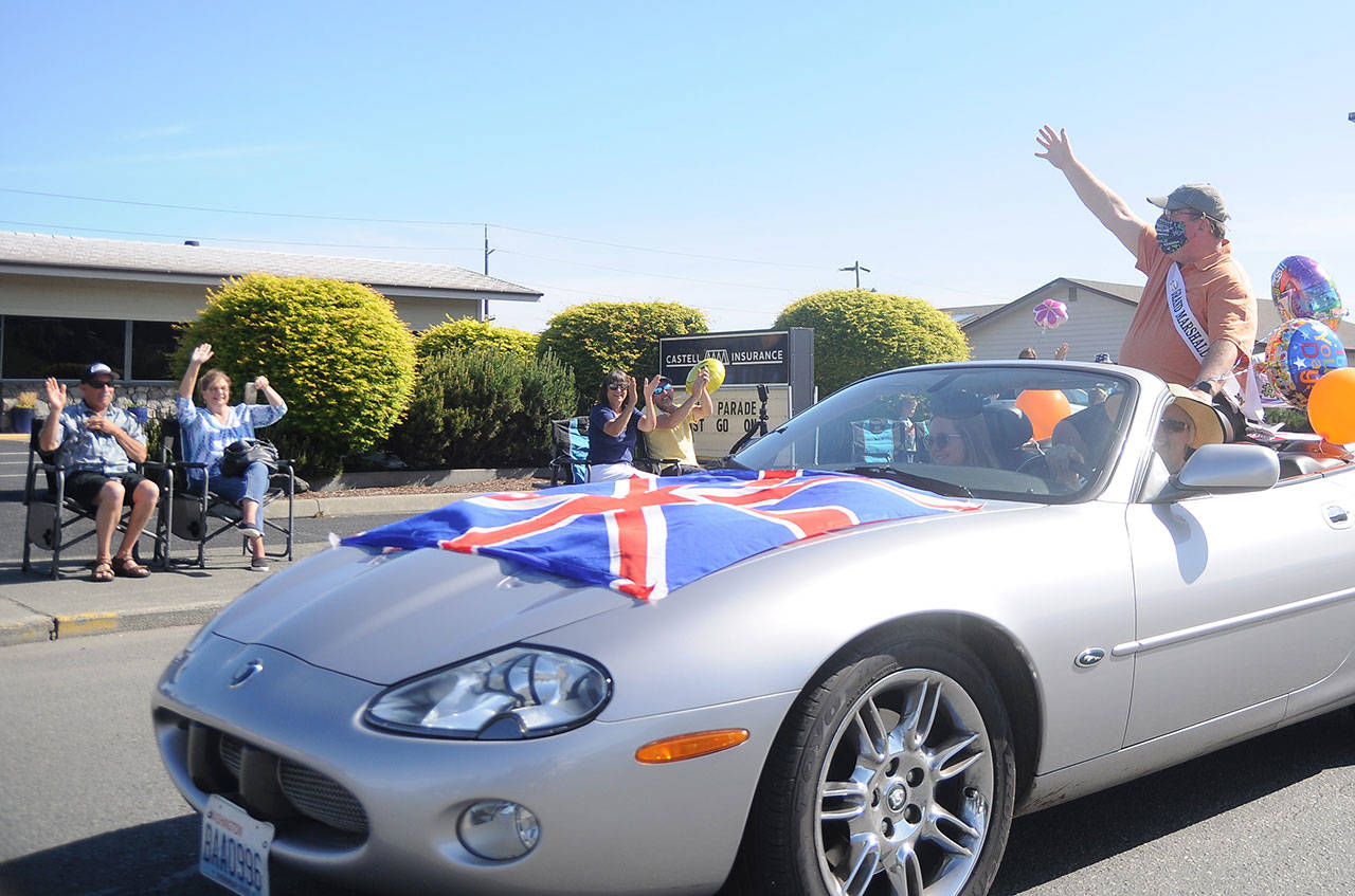 Phil Castell, the 2020 Irrigation Festival Grand Parade marshal, waves to a small gathering on what would have been the festival’s parade day Saturday, May 9, 2020. With the festival postponed until October, Castell hosted the small, one-car parade to mark the original day of the Grand Parade. (Michael Dashiell /Olympic Peninsula News Group)