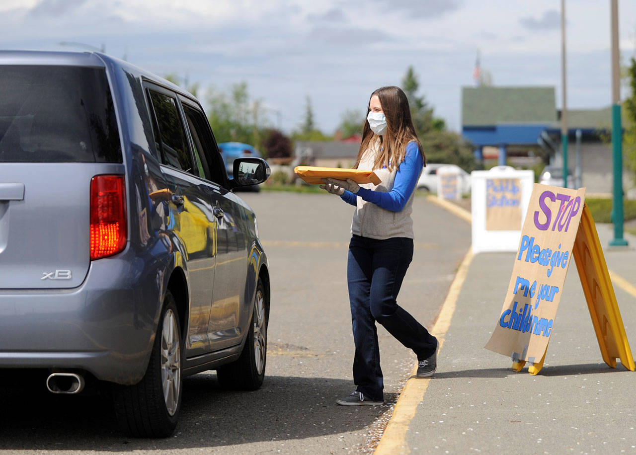 Jaysa Hill, a fourth-grade teacher at Helen Haller Elementary School, hands out a homework packet to a Haller student in April. (Michael Dashiell/Olympic Peninsula News Group file)