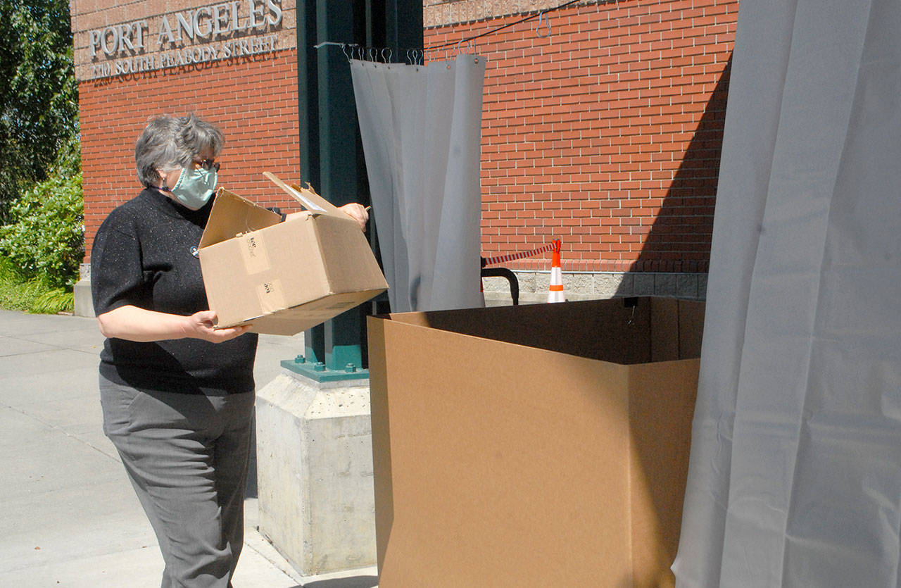 Mary Givins, a student librarian at the Port Angeles Public Library, takes part in a trial run to initiate curbside drop-off of returning books in the drive-in front of the library on Tuesday. The four North Olympic Library System libraries are to begin curbside returns. (Keith Thorpe/Peninsula Daily News)