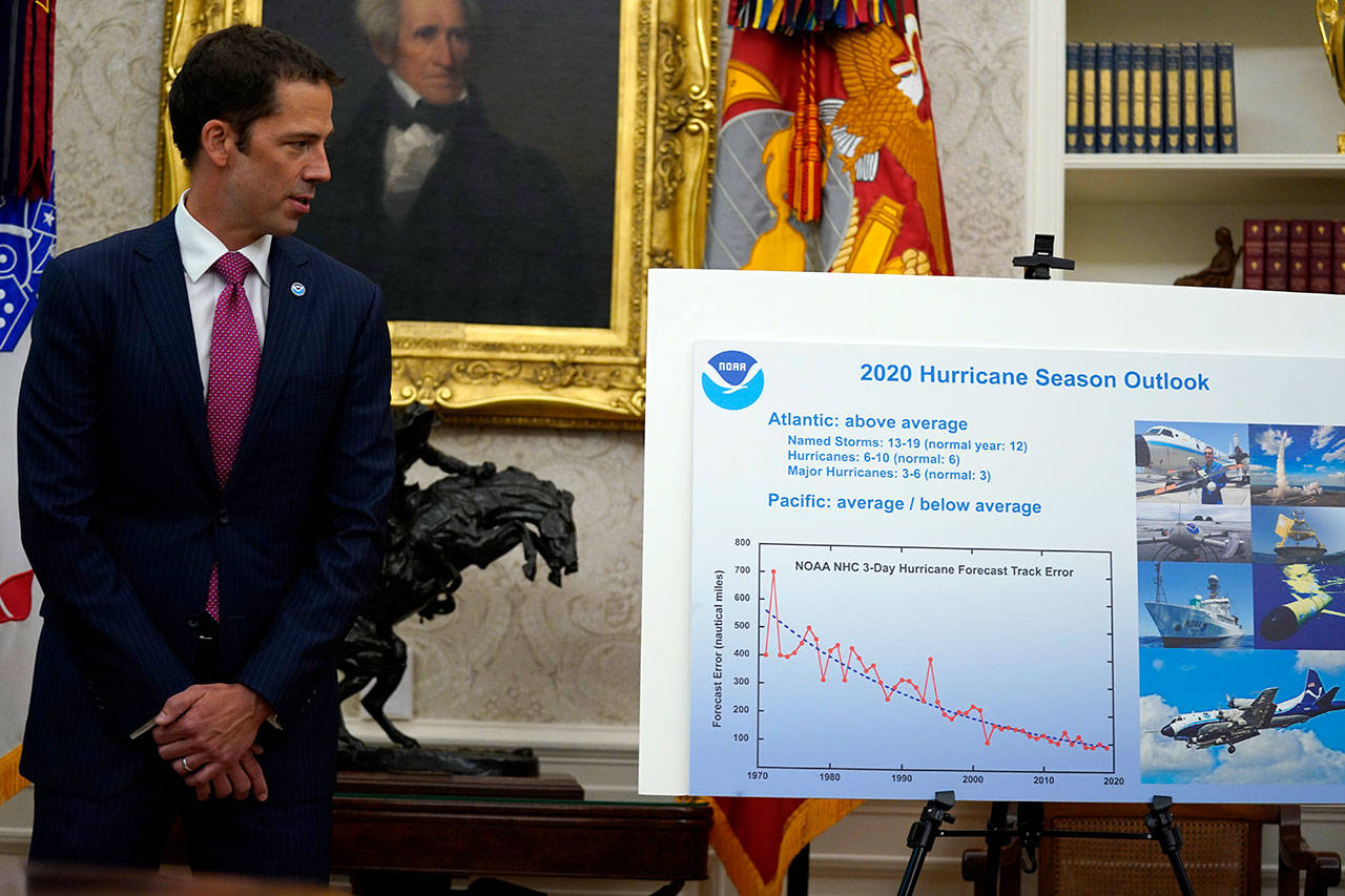 In this Thursday, May 28, 2020, file photo, Neil Jacobs, assistant Secretary of Commerce for Environmental Observation and Prediction, stands next to a chart during a briefing with President Donald Trump on the 2020 hurricane season in the Oval Office of the White House in Washington. A report from the National Academy of Public Administration released Monday, June 15, 2020, says that NOAA’s acting chief Jacobs and its then-communications director, Julie Kay Roberts, twice breached the agency’s rules designed to protect scientists and their work from political interference, putting out a press statement that “did not follow NOAA’s normal proves and appear to be the result of strong external pressure.” (Evan Vucci/Associated Press file)
