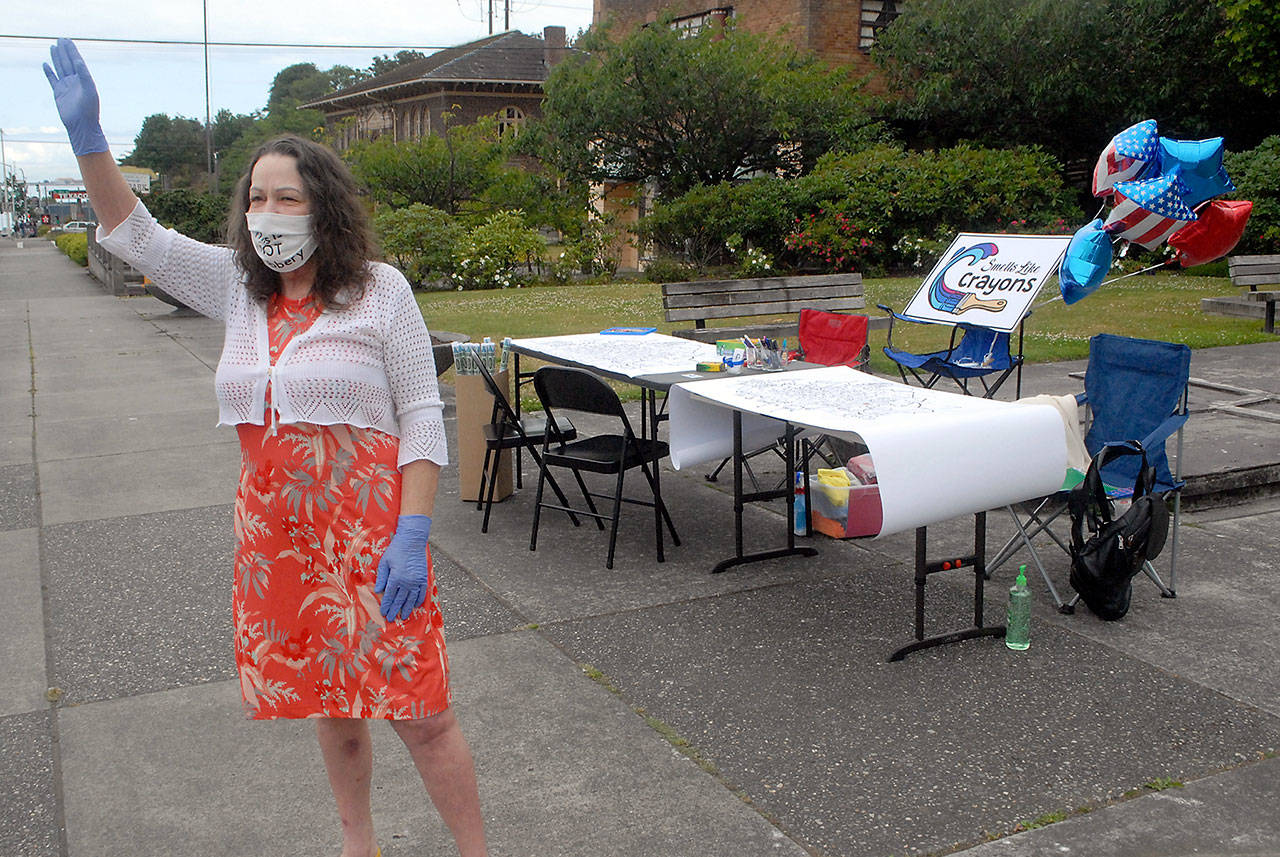 Ava Readdy of Port Angeles waves to traffic July 4 at Veteran’s Park in Port Angeles, urging people to sign a poster offering good wishes to the Spokane family who was questioned as to whether or not they were part of a leftist political movement and followed to their campsite outside of Forks on June 3. (Keith Thorpe/Peninsula Daily News)