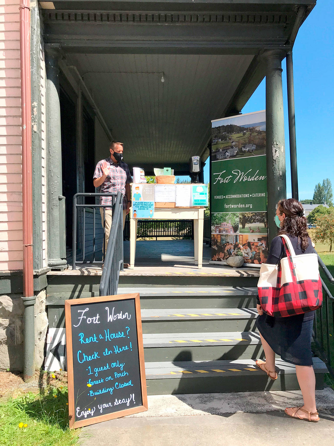 Fort Worden Public Development Authority front desk agent Jason Lamey, left, greets a guest who was checking into the PDA’s overnight accommodations as part of their soft-opening Tuesday, July 28, 2020. (Photo courtesy of Cody Griffith)