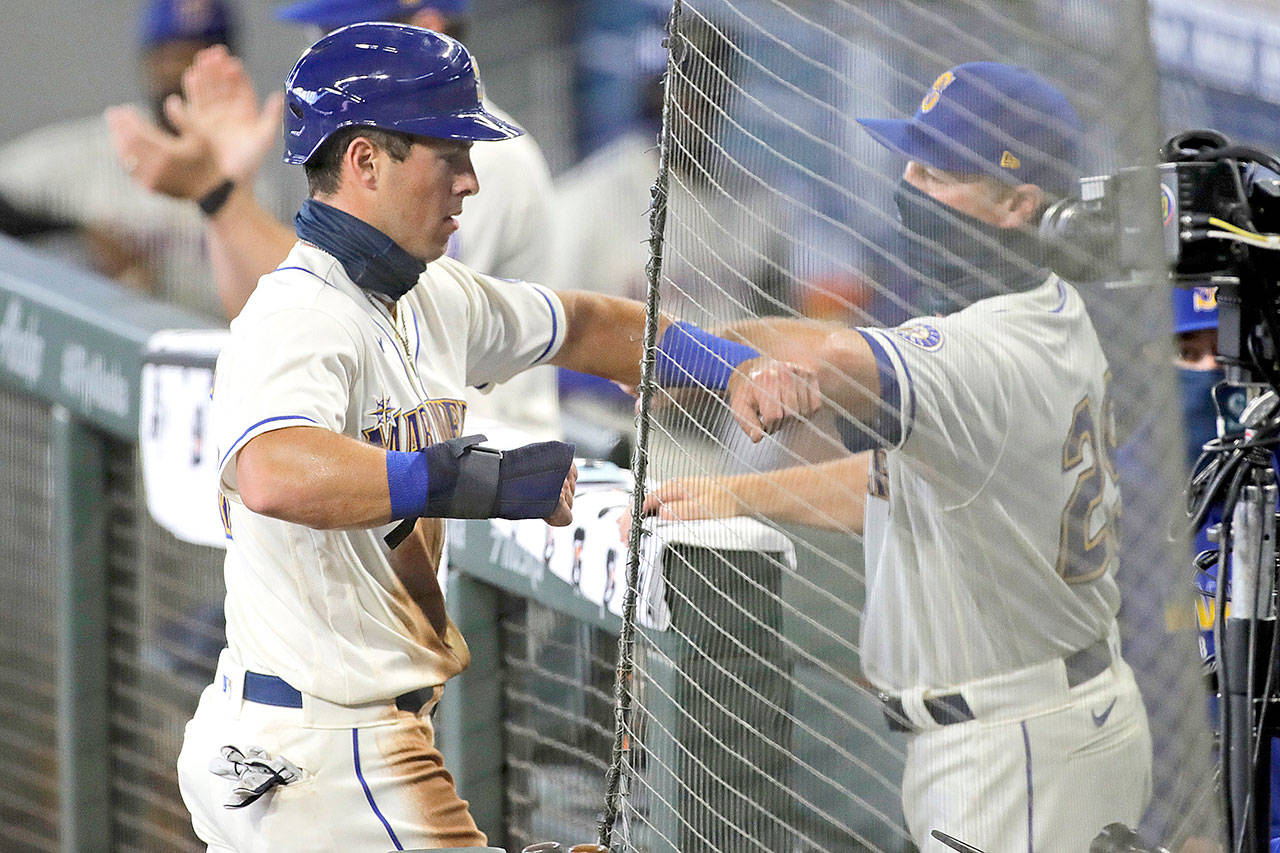 Seattle Mariners’ Dylan Moore, left, greets manager Scott Servais, after Moore scored on an RBI single hit by Daniel Vogelbach during the first inning of a baseball game against the Oakland Athletics, Sunday, Aug. 2, 2020, in Seattle. (AP Photo/Ted S. Warren)