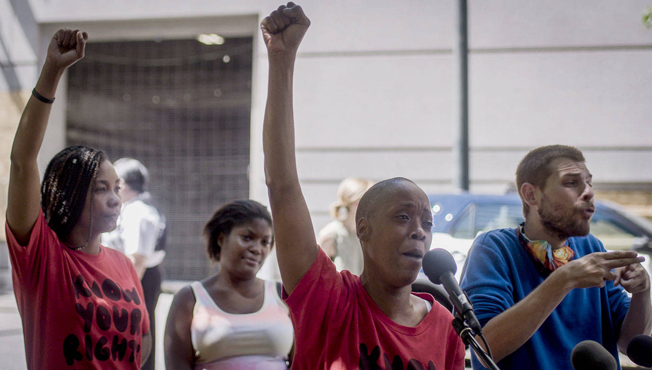 Demetria Hester, center, speaks to the media after being released from the Multnomah County Justice Center on Monday, Aug. 10, 2020, in Portland, Ore. Hester became a leading activist in the racial justice movement after she was assaulted by a white supremacist three years ago. Authorities said Hester won’t be charged following her arrest early Monday. Hester had been booked on suspicion of disorderly conduct and interfering with a police officer during the protest that began Sunday night. Hester’s arrest drew a sharp rebuke from national Black Lives Matter activists, who are increasingly focusing on demonstrations in Oregon’s largest city. (Brooke Herbert/The Oregonian via AP)