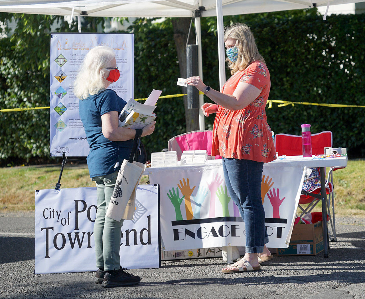 Port Townsend City Attorney Heidi Greenwood, right, hands an EngagePT card to Bonnie Walters, a painter and jewelry-maker who recently moved from Sausalito, Calif., to Port Townsend with her husband. “I can’t wait to get engaged,” she said. “This town is just so vibrant.” (Nicholas Johnson/Peninsula Daily News)