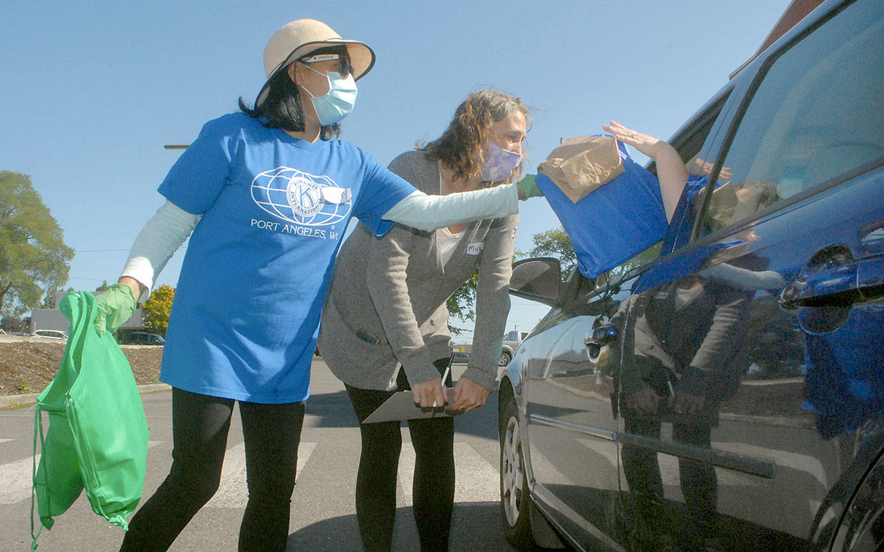 Lyn Gay, a member of the Kiwanis Club of Port Angeles, left, and Michell Gentry of Americorps help distribute school supplies during the Port Angeles School District’s annual back to school event, held Saturday at the Lincoln Center. Organizers arranged this year’s supplies giveaway as a drive-thru event to mitigate the danger of COVID-19 in an enclosed space. (Keith Thorpe/Peninsula Daily News)