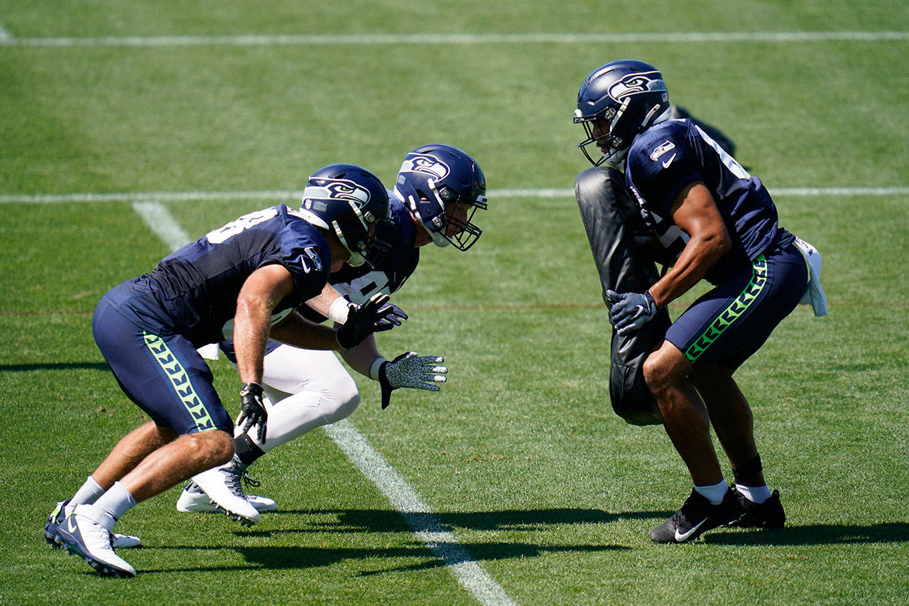 Seattle Seahawks’ Greg Olsen, left, and Will Dissly begin to rush toward Tyler Mabry on Tuesday, Aug. 18, 2020, during an NFL football training camp in Renton, Wash. (Elaine Thompson/Associated Press)