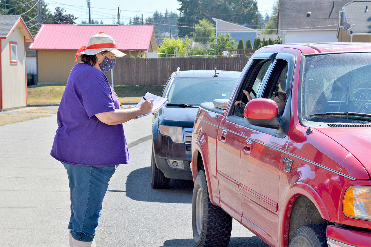 Paraeducator Paula Walters passes out Chromebooks to Seaview students, drive-thru style, at Jefferson Elementary.