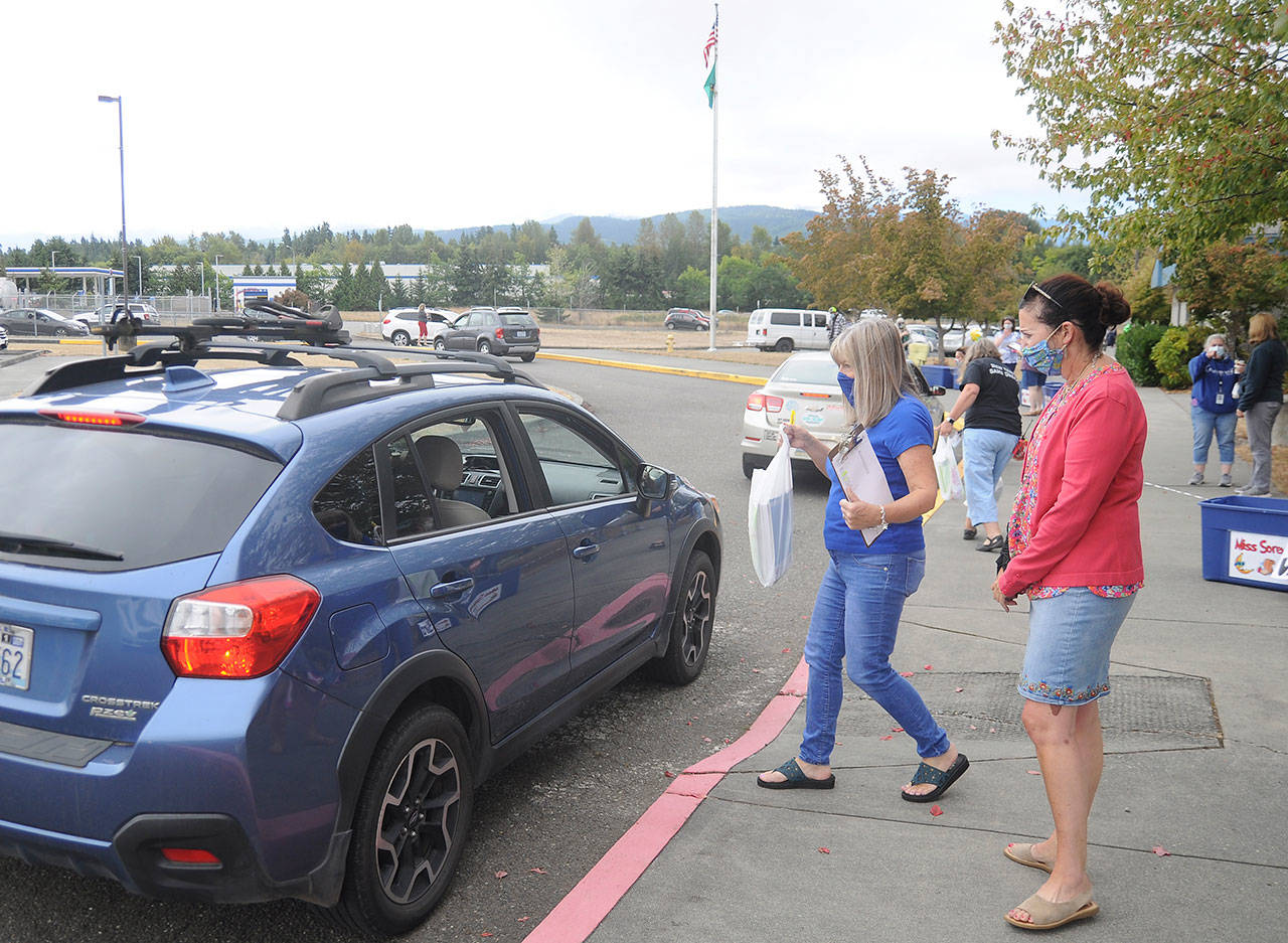 Third-grade teacher Sheri Burke, center, and reading specialist Natalie Fortier hand out packets of school curriculum and materials at Greywolf Elementary School on Sept. 2, the first day of school for Sequim students. Sequim Gazette photo by Michael Dashiell                                (Michael Dashiell/Olympic Peninsula News Group)