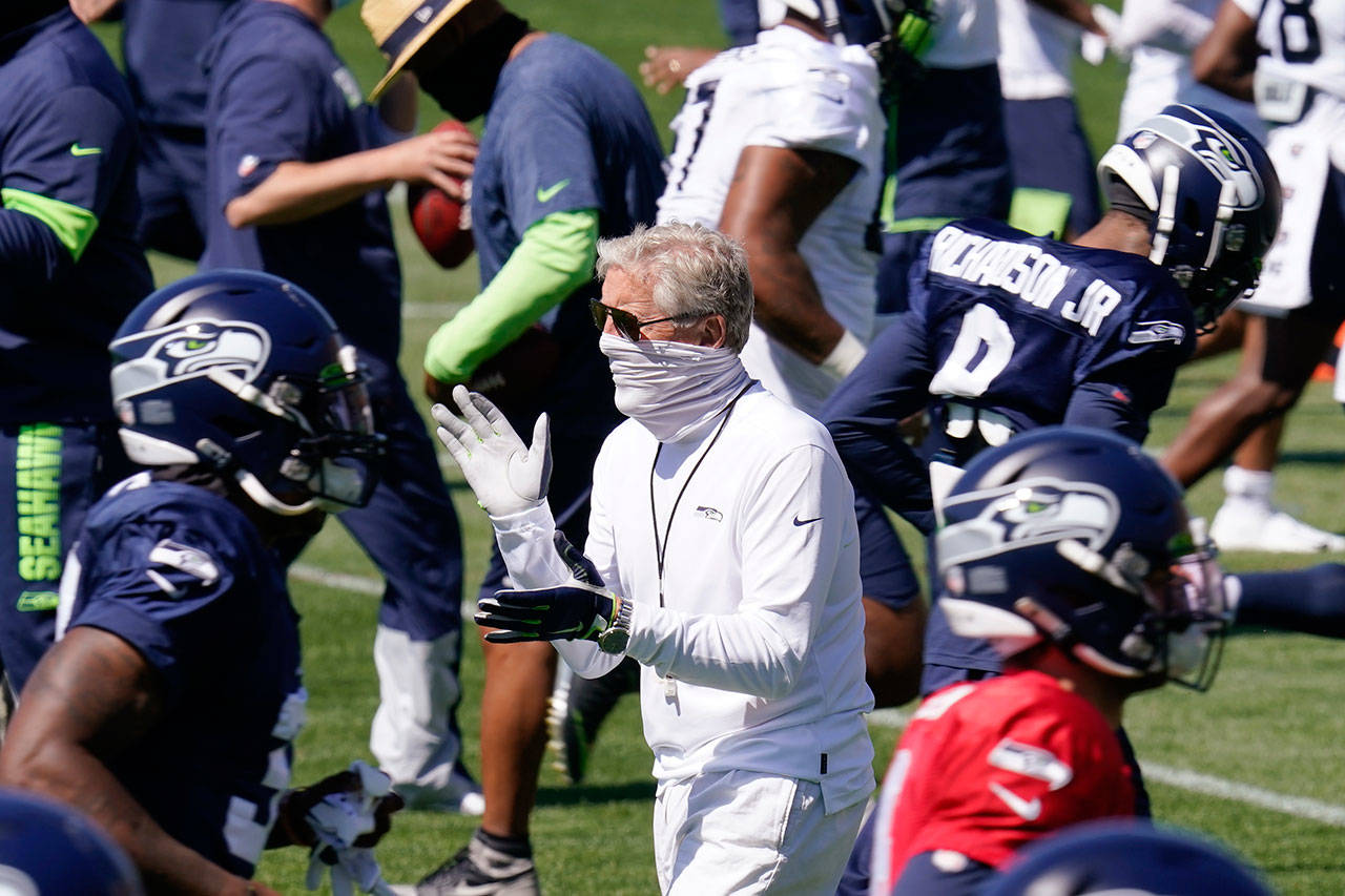 Seattle Seahawks head coach Pete Carroll applauds as players run past Sunday, Aug. 30, 2020, during an NFL football training camp in Renton. (Elaine Thompson/Associated Press)