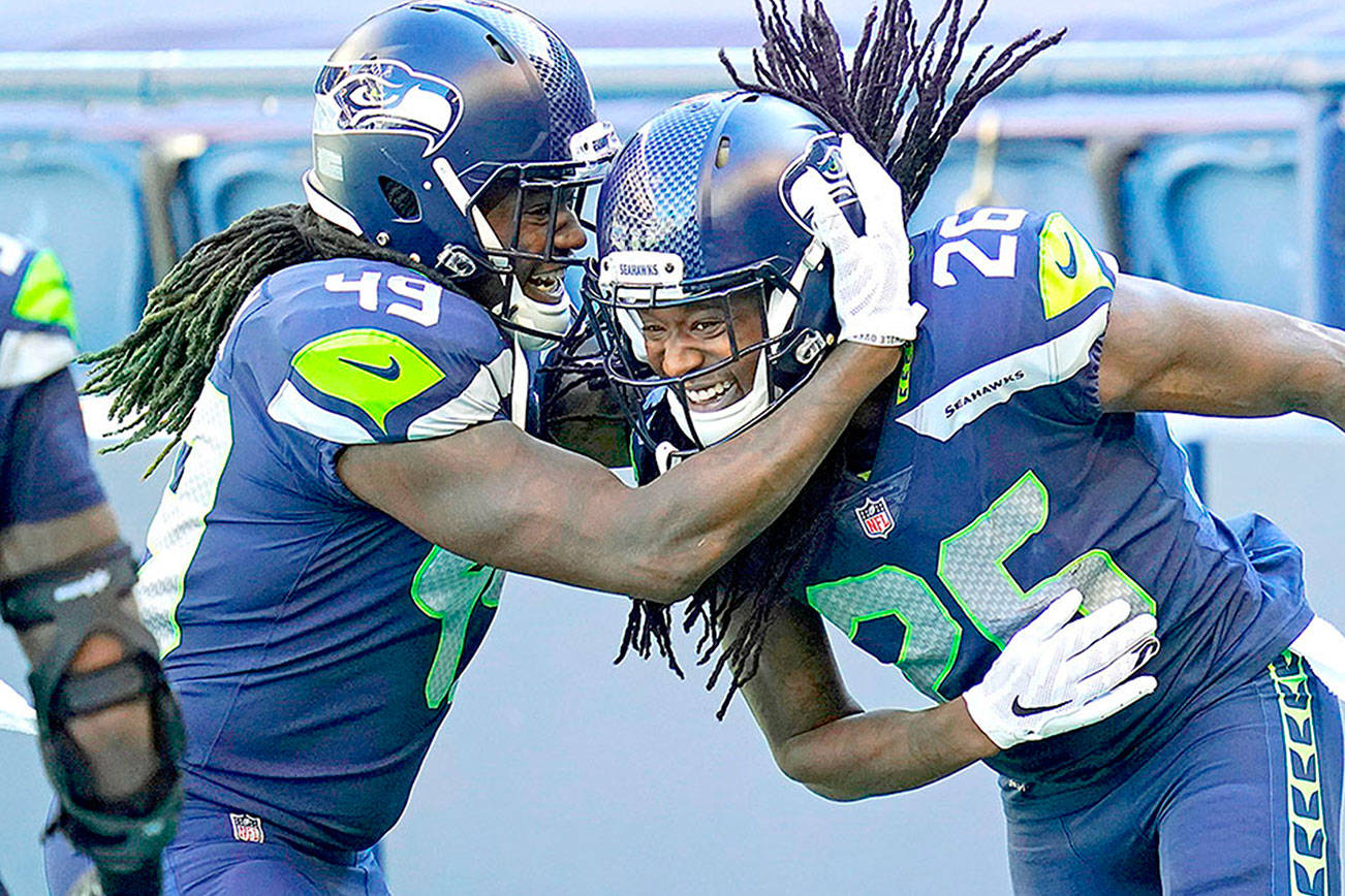 Seattle Seahawks cornerback Shaquill Griffin (26) is greeted by his twin brother, outside linebacker Shaquem Griffin (49), after Shaquill Griffin intercepted a pass against the Dallas Cowboys on Sunday in Seattle. (AP Photo/Elaine Thompson)