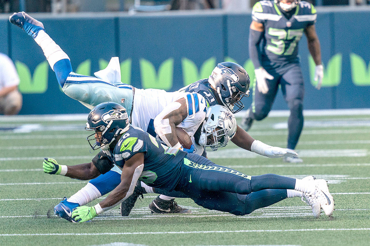 Dallas Cowboys running back Ezekiel Elliott, middle, is tackled by Seattle Seahawks linebacker Bobby Wagner, top, and defensive back Ugo Amadi on Sunday in Seattle. The Seahawks won 38-31. (Stephen Brashear/Associated Press)