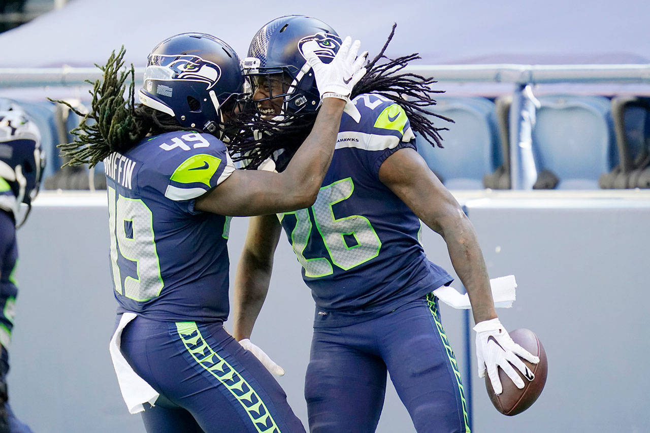 Seattle Seahawks cornerback Shaquill Griffin (26) is greeted by his twin brother, outside linebacker Shaquem Griffin (49) after Shaquill Griffin intercepted a pass against the Dallas Cowboys during the first half of an NFL football game Sunday, Sept. 27, 2020, in Seattle. (Elaine Thompson/Associated Press)