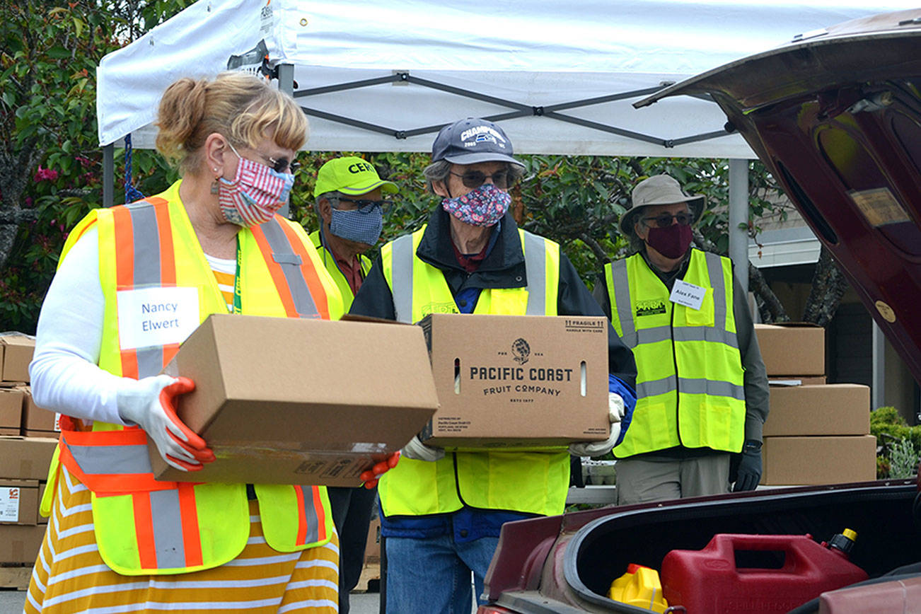 Volunteers Nancy Elwert and Bruce Leigh with Community Emergency Response Teams (CERT) ready to place food boxes in a trunk on June 10 at Sequim High School. The program, now held at Trinity United Methodist Church, continues twice monthly through December. Matthew Nash/Olympic Peninsula News Group
