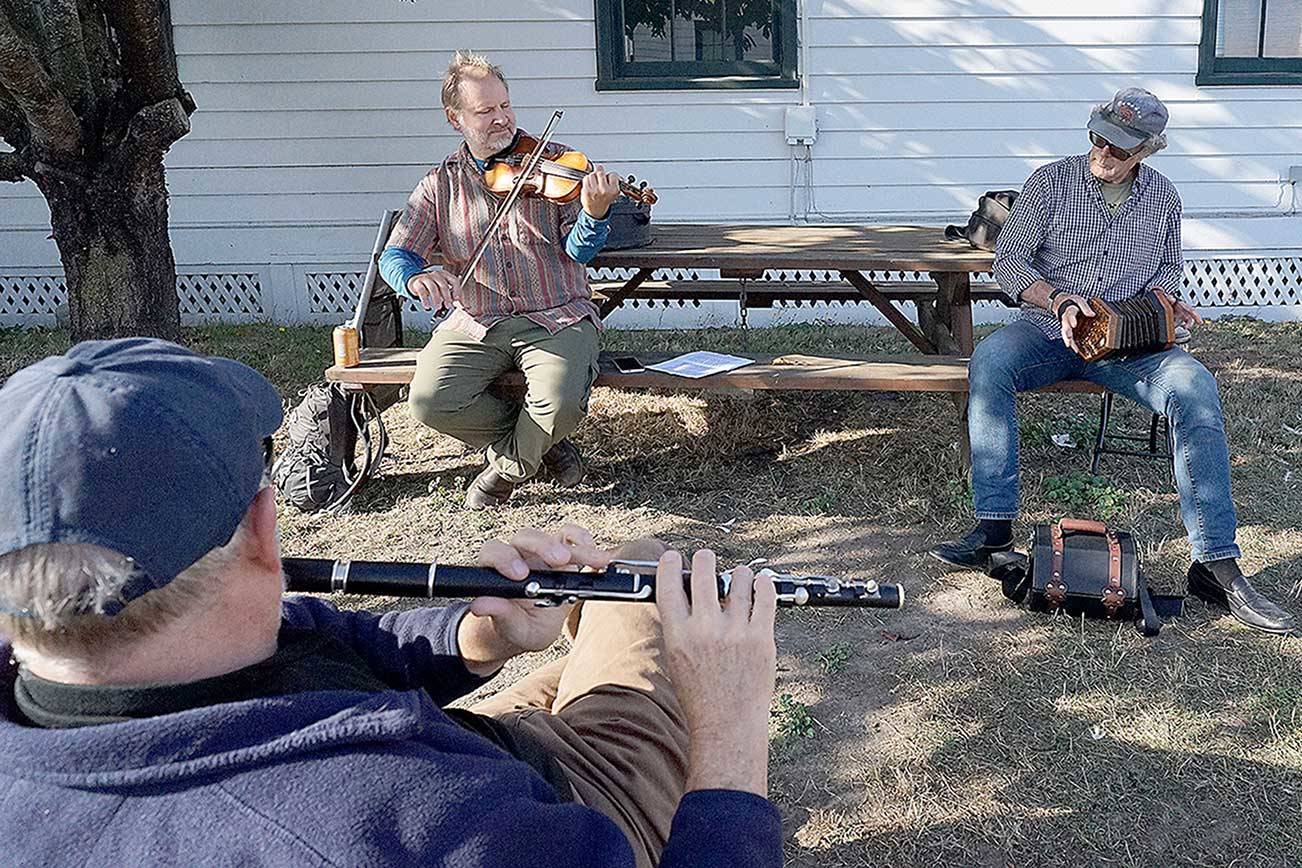 Three friends spend their Monday afternoon playing Irish traditional tunes while sitting socially distanced on a crisp, sunny October day at Point Hudson in Port Townsend. Mark Morris, foreground, of Ashland, Ore., plays the concert flute while Dave Lewicki, left, plays the fiddle and Alex Bradbury plays the concertina. Both Lewicki and Bradbury are Port Townsend residents. (Nicholas Johnson/Peninsula Daily News)