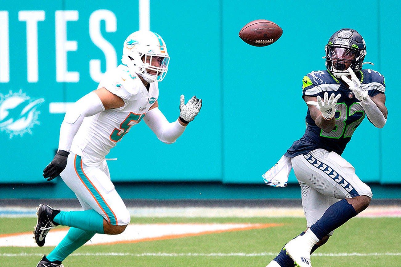 Seattle Seahawks running back Chris Carson (32) catches the ball in front of Miami Dolphins linebacker Kyle Van Noy (53) during an NFL football game, Sunday, Oct. 4, 2020, in Miami Gardens, Fla. (AP Photo/Doug Murray)