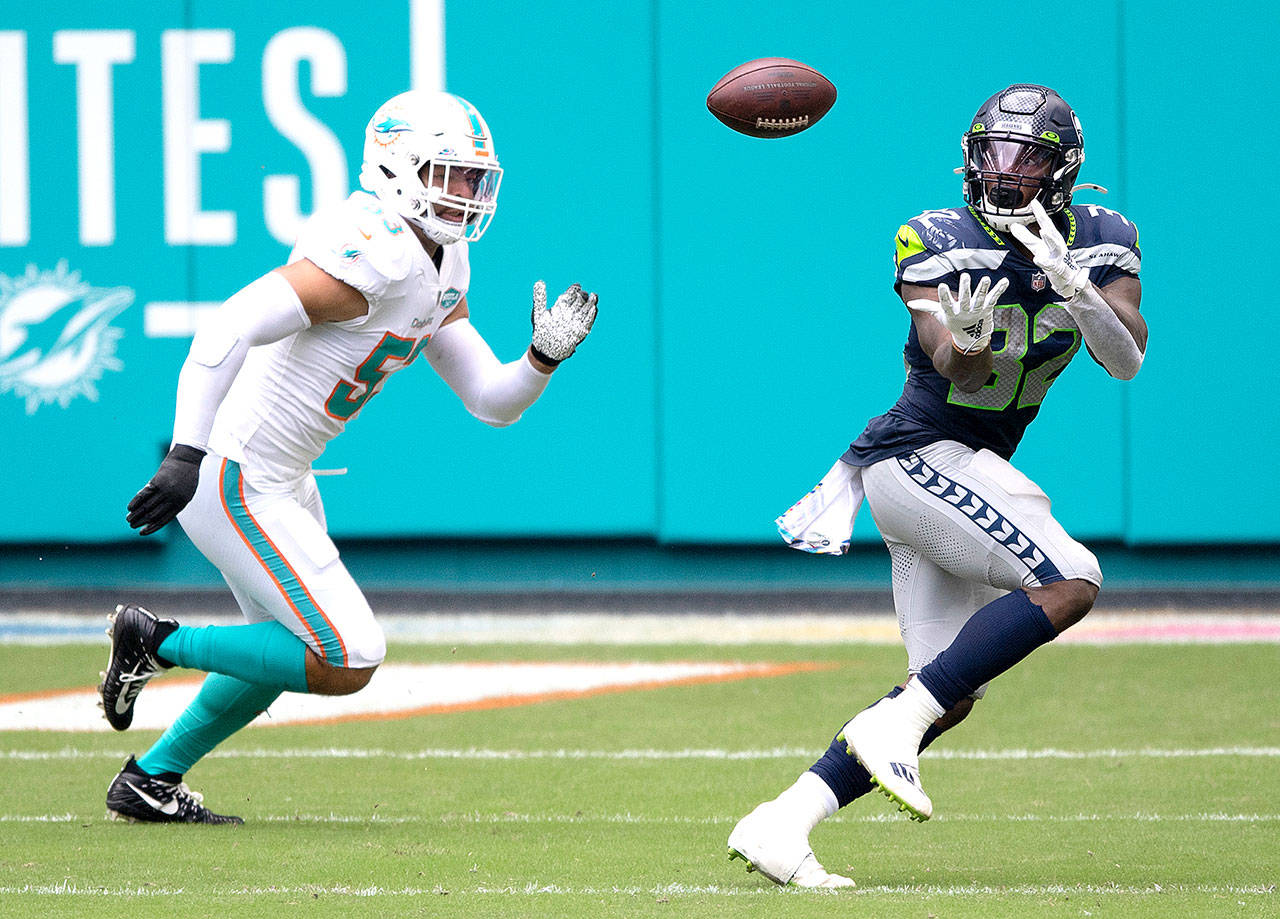 Seattle Seahawks running back Chris Carson (32) catches the ball in front of Miami Dolphins linebacker Kyle Van Noy (53) during an NFL football game, Sunday, Oct. 4, 2020, in Miami Gardens, Fla. (AP Photo/Doug Murray)