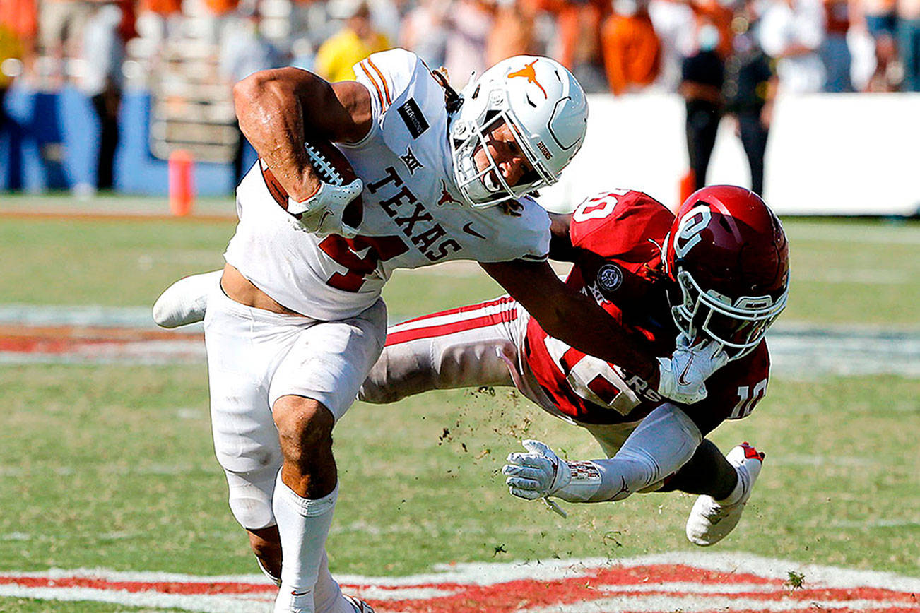 Texas wide receiver Jordan Whittington (4) tries to break a tackle from Oklahoma defensive back Pat Fields (10) during overtime of an NCAA college football game in Dallas, Saturday, Oct. 10, 2020. Oklahoma defeated Texas 53-45 in four overtimes.(AP Photo/Michael Ainsworth)