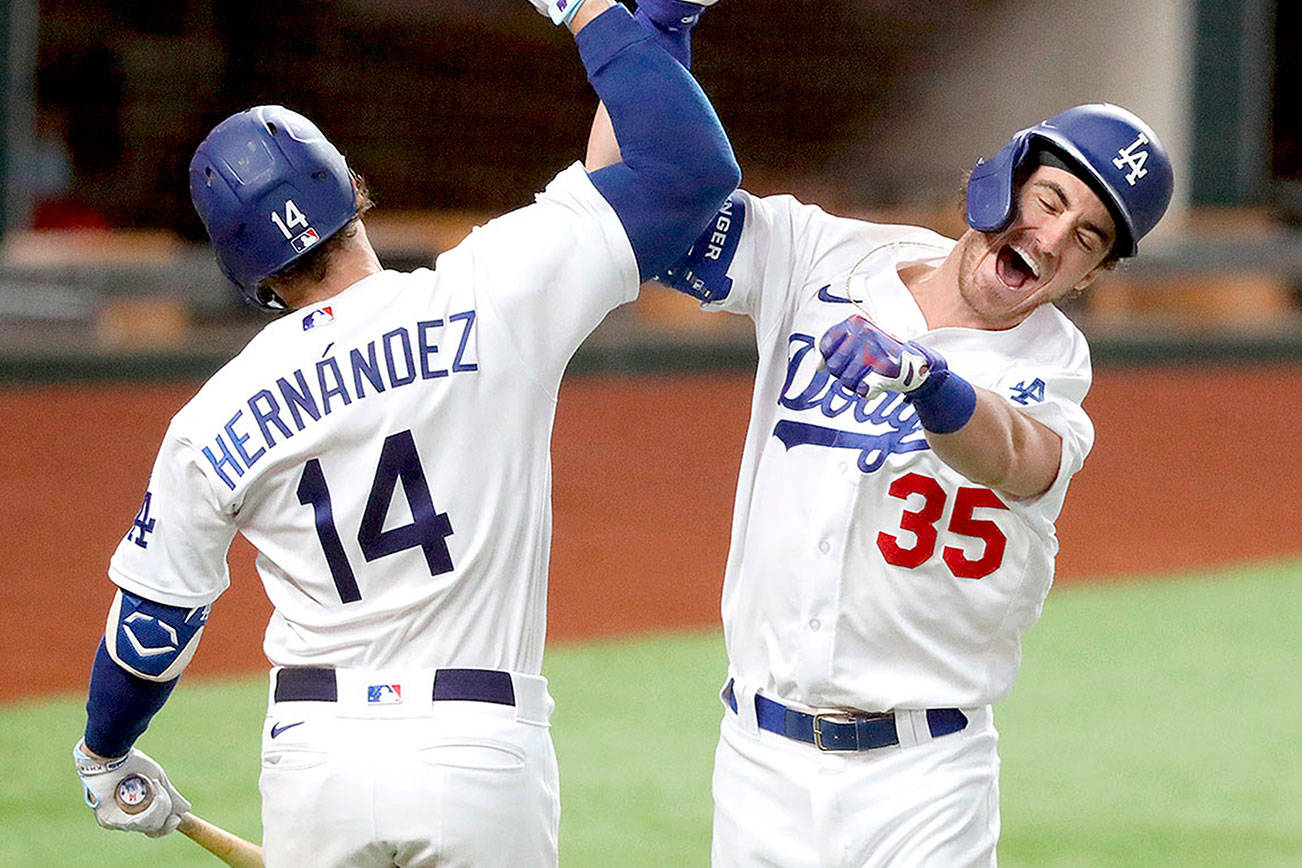 Los Angeles Dodgers' Cody Bellinger, right, celebrates his solo home run with Enrique Hernandez against Atlanta Braves relief pitcher Chris Martin during the seventh inning in Game 7 of a baseball National League Championship Series, Sunday, Oct. 18, 2020, in Arlington, Texas. (Curtis Compton/Atlanta Journal-Constitution via AP)
