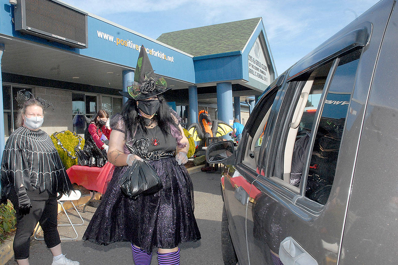 Keith Thorpe/Peninsula Daily NewsB
Kayleen McDonald of the Sequim unit of the Boys & Girls Clubs of the Olympic Peninsuila delivers bagged lunches to a waiting car as unit director Tessa Jackson looks on at left during a drive-thru Halloween in front of the organization's Sequim facility. Besides lunch bags, trick-or-treaters were offered hats, treats and coloring books.